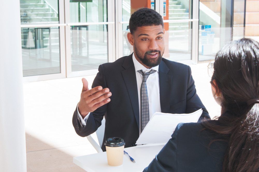 Businessman gesturing and talking with a colleague at an outdoor cafe