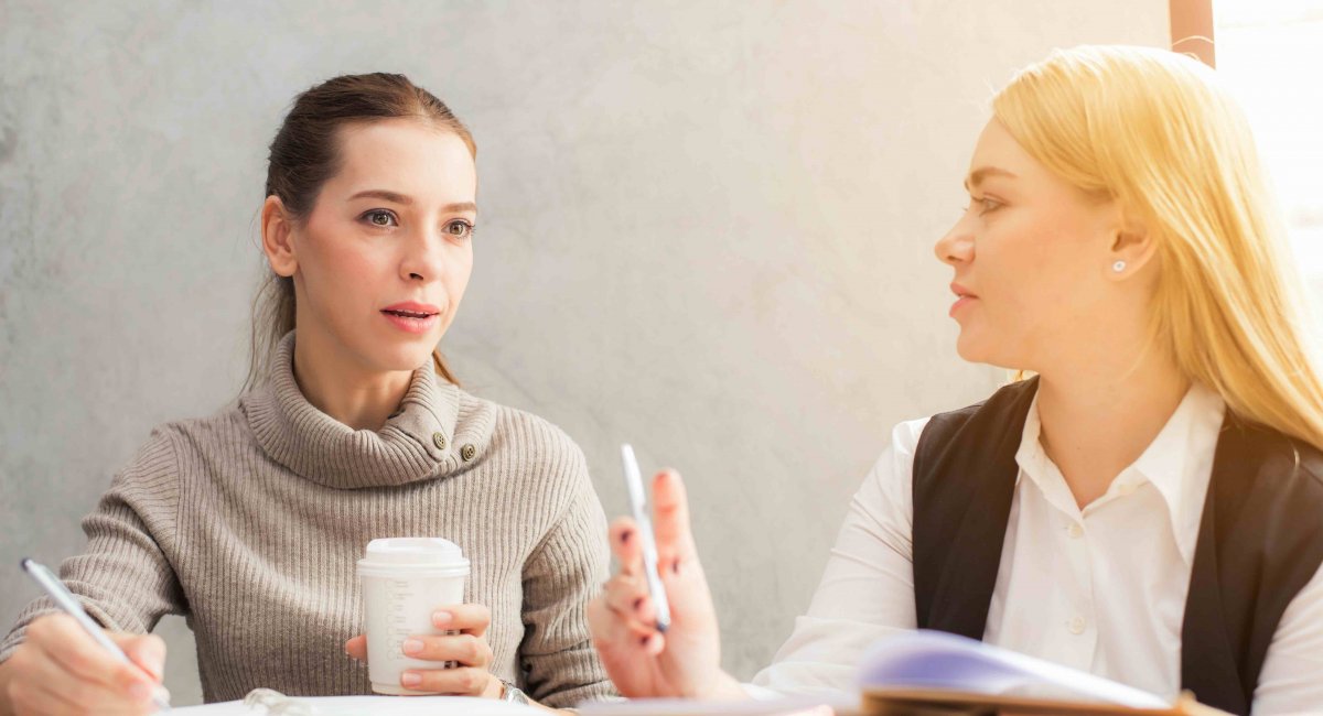 Let me interrupt you here... Two young women talking in an office