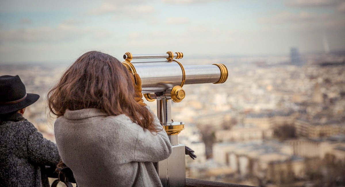 What have you learned? Person using telescope on skyscraper looking over city
