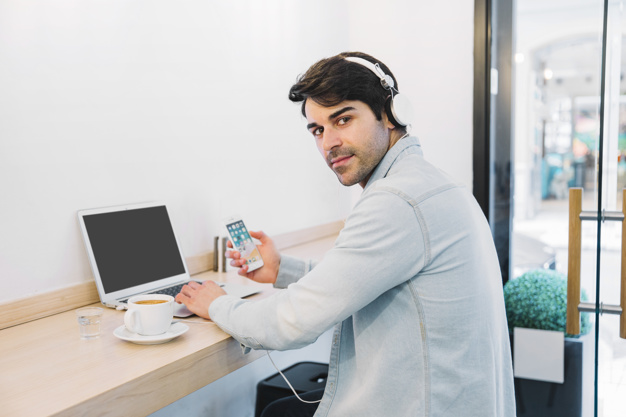 Man at laptop with smartphone and coffee