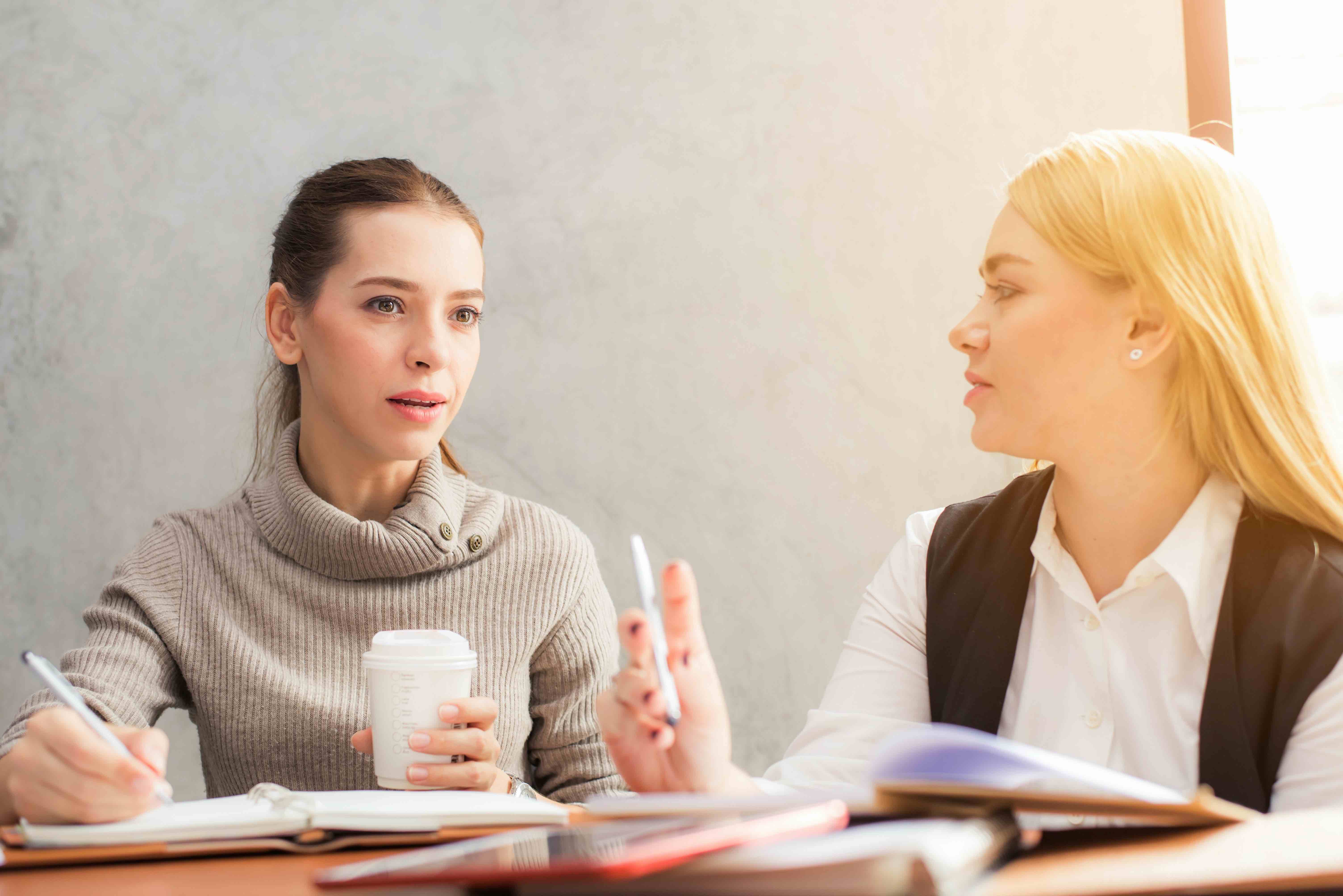 Two young women talking in an office