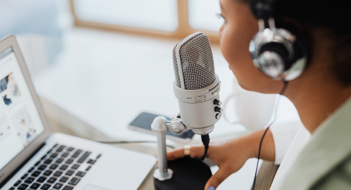 Woman with headset speaking over a condenser microphone