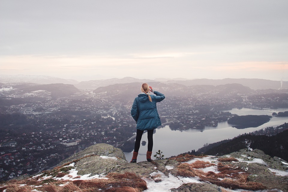 Person standing on top of a mountain looking at the view