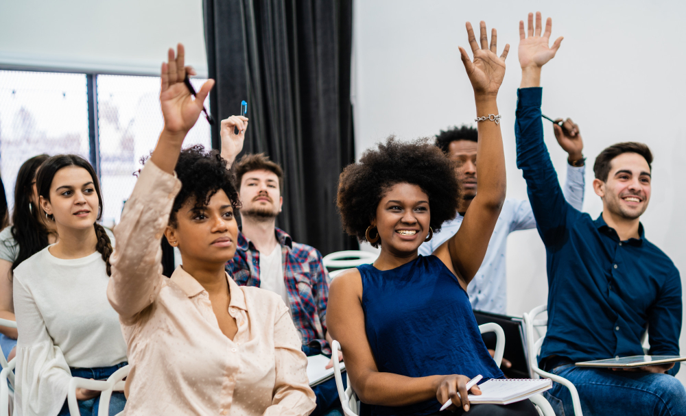 A group of young people raising their hands in a classroom