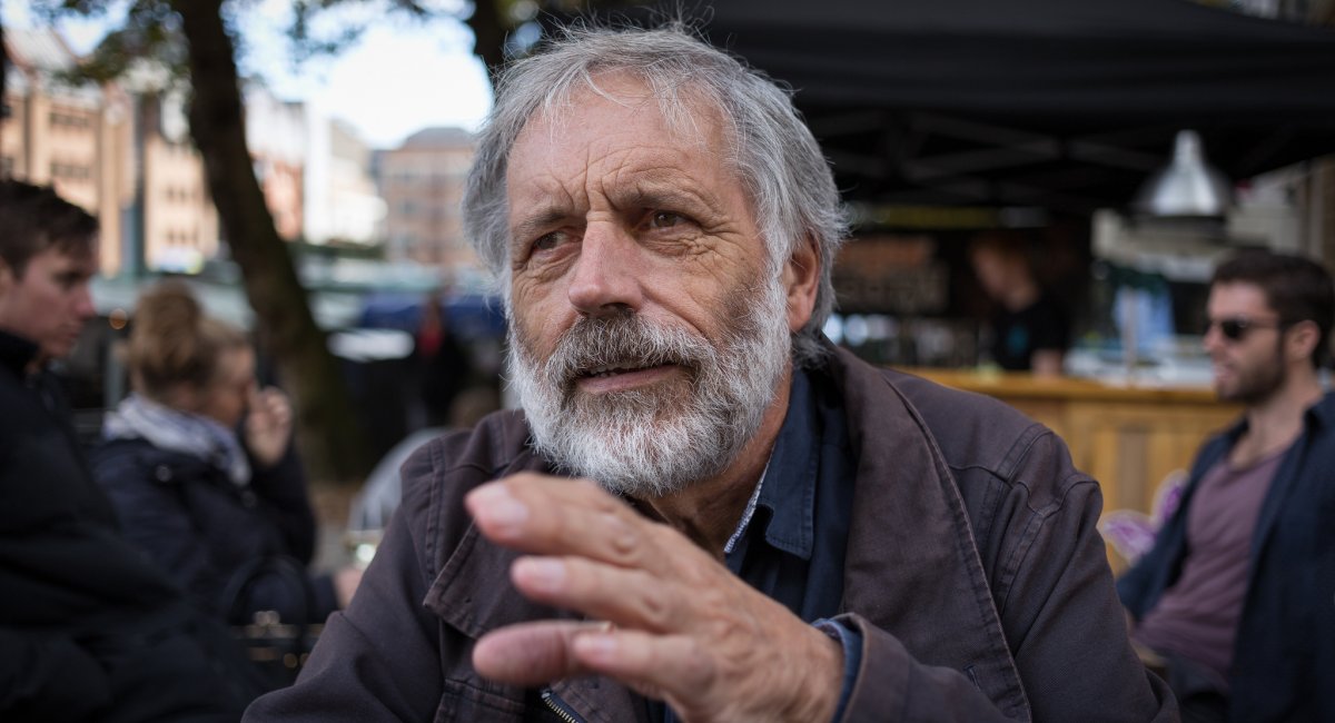 Old man sitting outside gesturing while talking