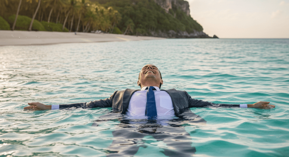 A man in a suit floats on his back in a tropical ocean