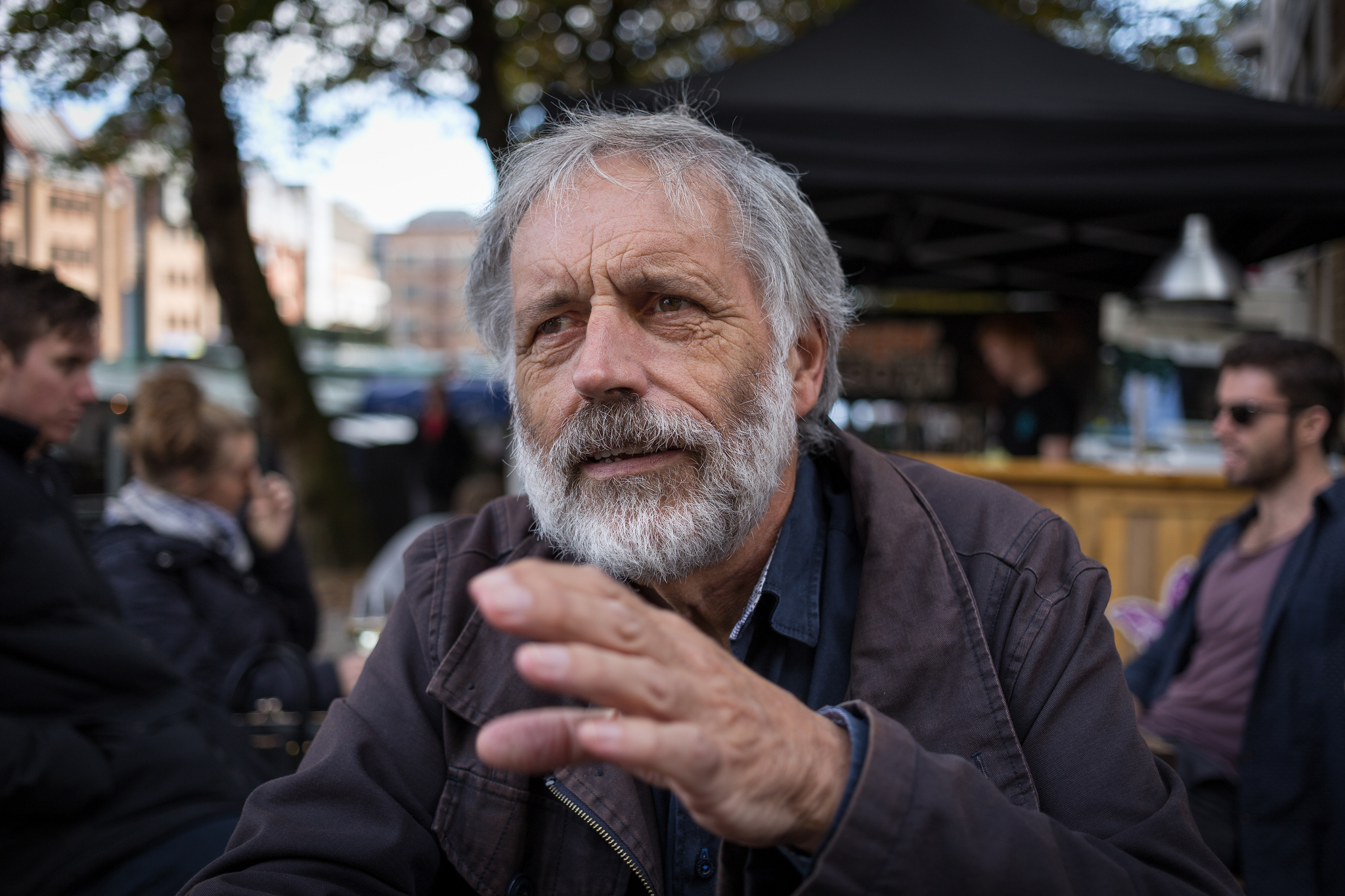 Old man sitting outside gesturing while talking