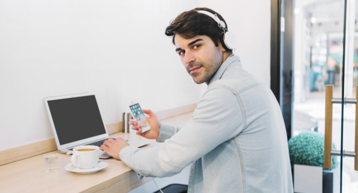 Man at laptop with smartphone and coffee