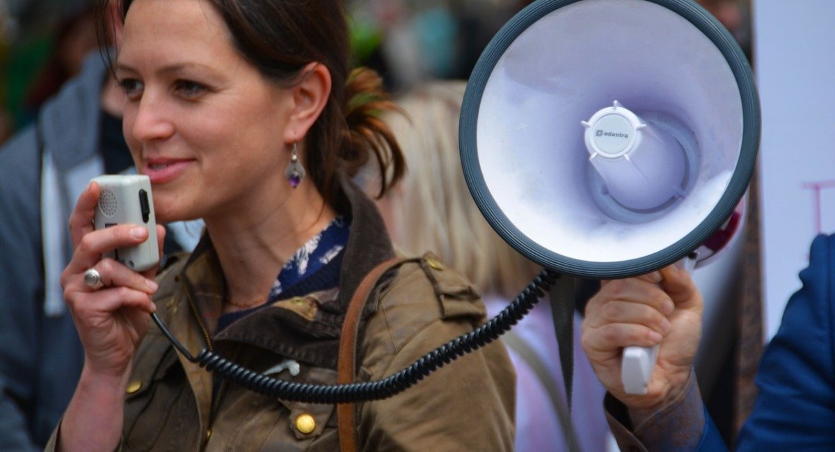 Young woman speaking with a megaphone at a rally